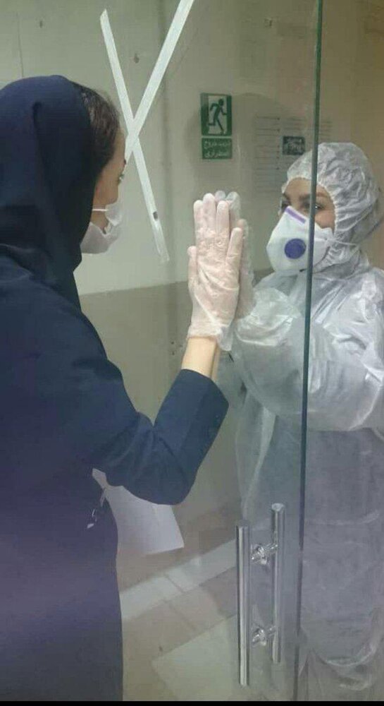 (عکس) تصویر اثرگذار از دو پرستار در مرز قرنطینه بیمارستان