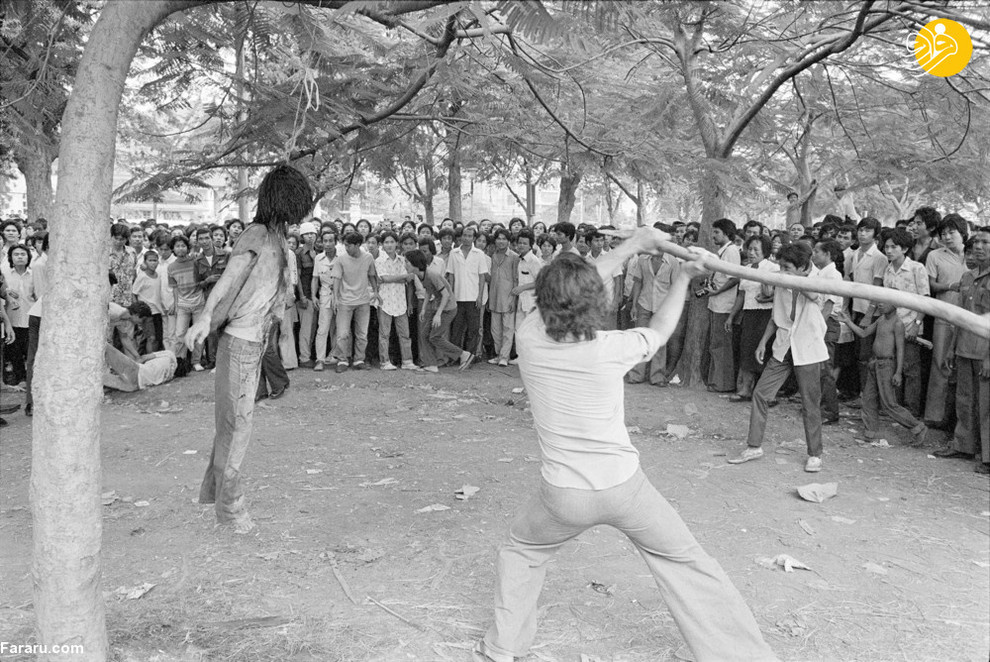 6 اکتبر 1976/ یکی از اعضای یک جناح سیاسی در تایلند در حال چوب زدن به جنازه یک دانشجوی به دار آویخته در خارج از دانشگاه بانکوک